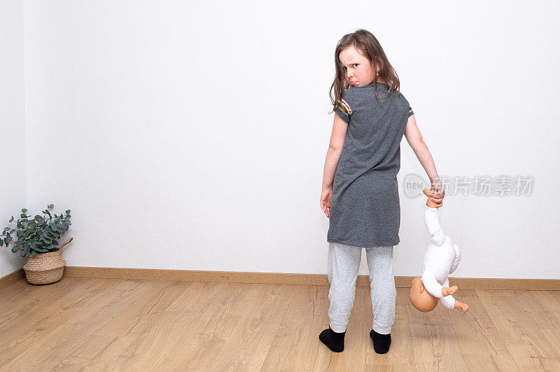 一个7 - 9岁的白人女孩的肖像，非常沮丧，手里拿着一个旧娃娃，转身往回看。怨恨和懊恼的一系列情绪。